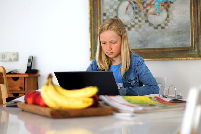 A young girl working from home on her laptop at a table