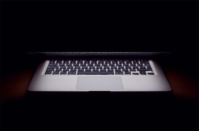 Laptop, partly closed lid, in a darkened room Laptop, partly closed lid, in a darkened room