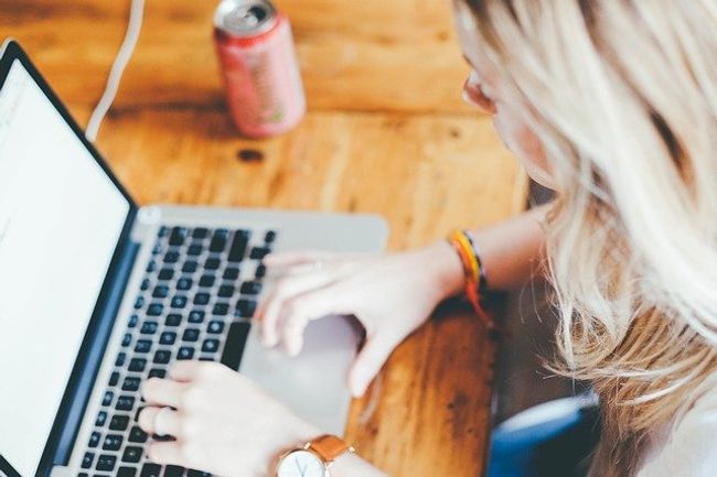 A lady working on her laptop on a wooden table. A lady working on her laptop on a wooden table.