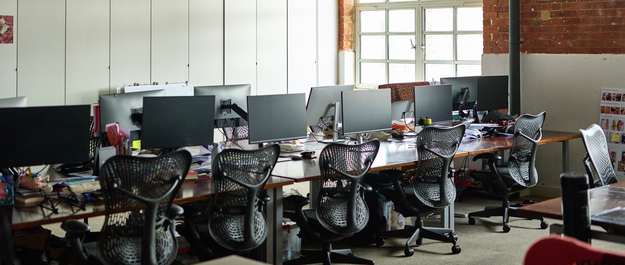 Industrial style office interior with pipework, exposed brick walls and ergonomic furniture