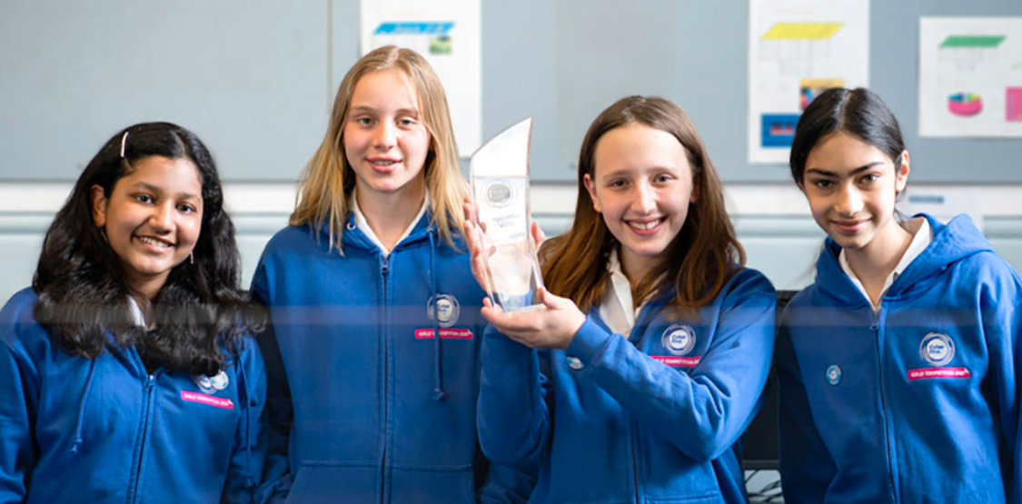 Four of the girls who took part in the CyberFirst Girls Competition holding a trophy