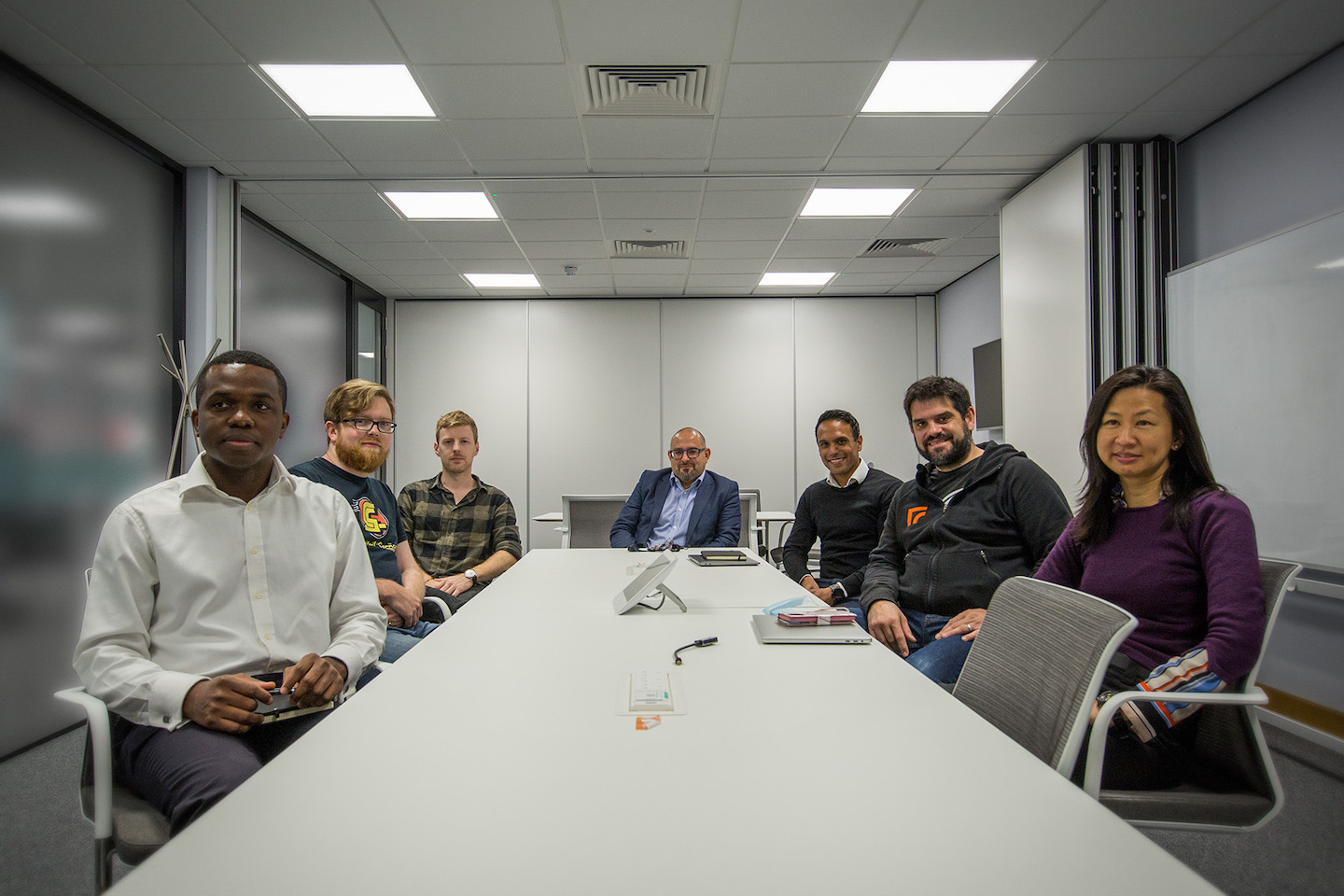 A group of people at work around a table holding a video conference