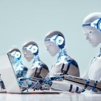Humanoid robots working at laptops