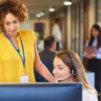 Two female colleagues discussing work matters in front of a computer monitor