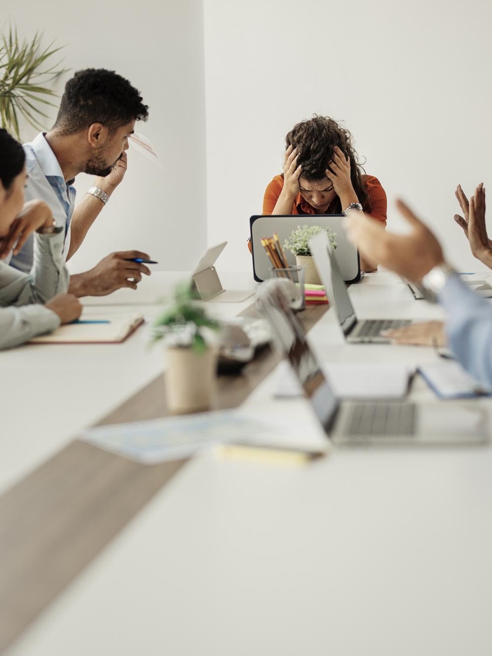 Meeting, with Chair holding head in hands during animated discussion