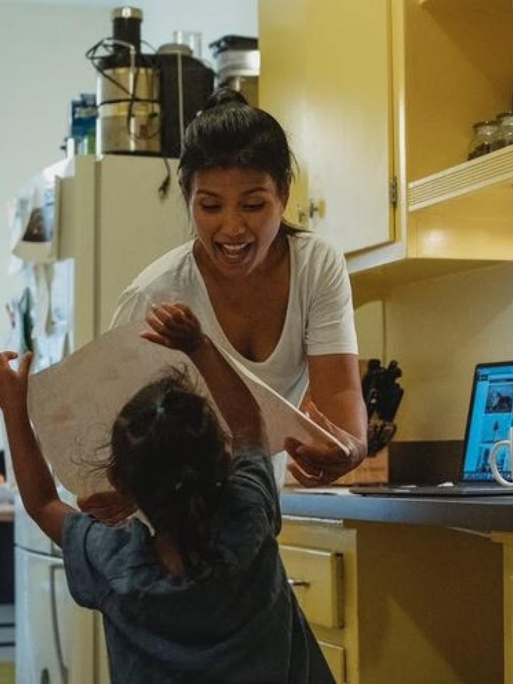 Parent and child in kitchen trying to work from home and home school child