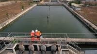 birds eye view of a water plant with two workers in orange high viz looking at the water pumps