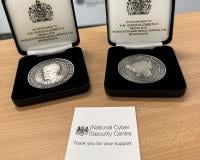 Two challenge coins sat on a desk in cases