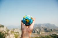 A small globe being held aloft in a hand