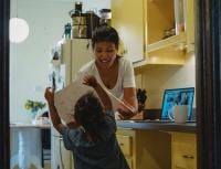 Parent and child in kitchen trying to work from home and home school child