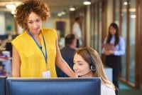 Two female colleagues discussing work matters in front of a computer monitor