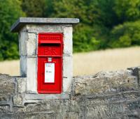 Image shows a UK post box embedded in a stone wall