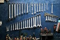 Image shows wrenches and spanners of various sizes hanging on a wall